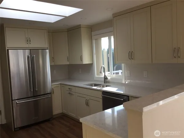 a kitchen with stainless steel appliances a refrigerator a sink and white cabinets