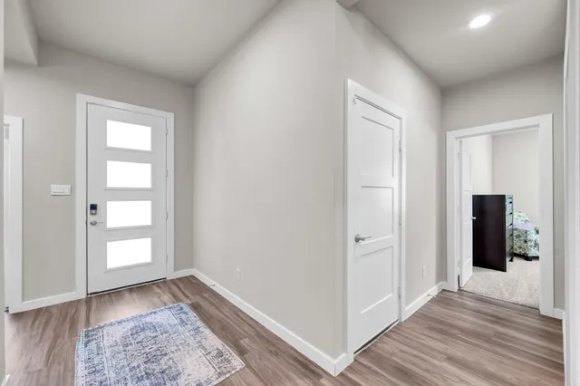 an empty room with wooden floor cabinet and front door