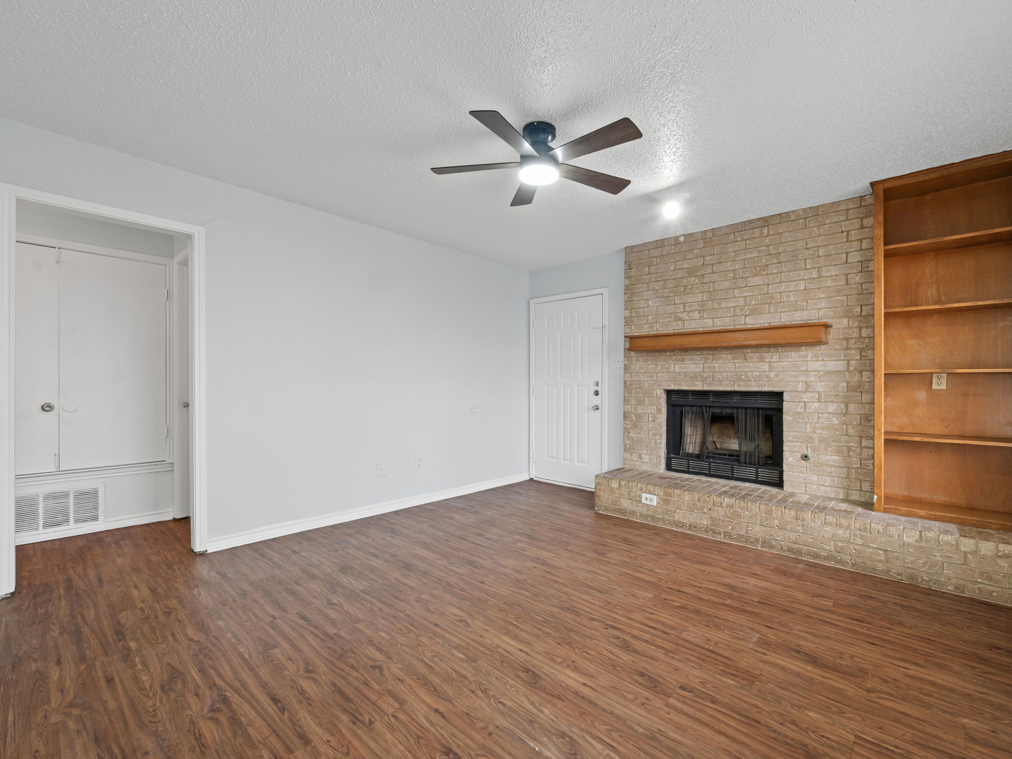 1816 Rawhide Loop, Unit 1822 Round Rock, TX 78681 - Photo 6 of 17 Unfurnished living room featuring ceiling fan, a textured ceiling, dark wood-type flooring, and a fireplace