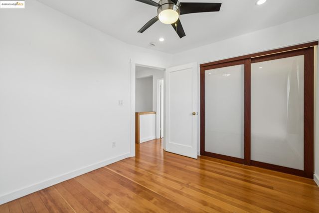 an empty room with wooden floor chandelier fan and windows
