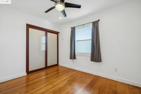 an empty room with wooden floor closet and windows