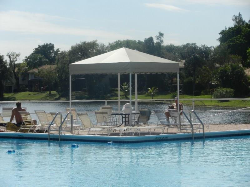 3760 Inverrary Drive, Unit 2H Lauderhill, FL 33319 - Photo 11 of 23 a view of a lake with a table and chairs under an umbrella