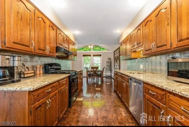 a kitchen with stainless steel appliances granite countertop a stove a sink and a microwave