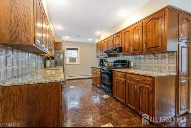 a kitchen with stainless steel appliances granite countertop a refrigerator a stove top oven and cabinets