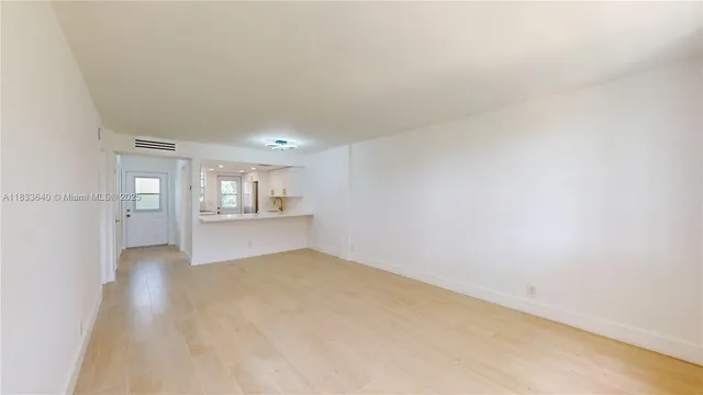 a view of kitchen and empty room with wooden floor
