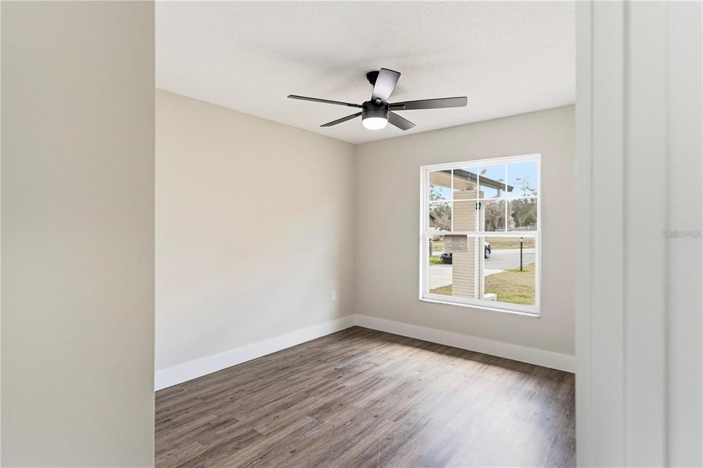 616 Water Road Ocala, FL 34472 - Photo 19 of 32 an empty room with wooden floor chandelier fan and windows