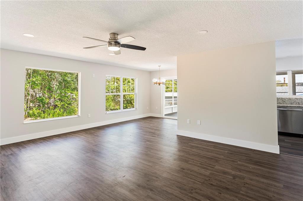 616 Water Road Ocala, FL 34472 - Photo 4 of 32 an empty room with wooden floor chandelier fan and windows
