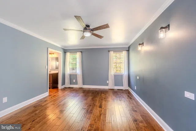 an empty room with wooden floor fan and windows
