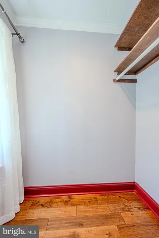 a view of an empty room with a window and a kitchen