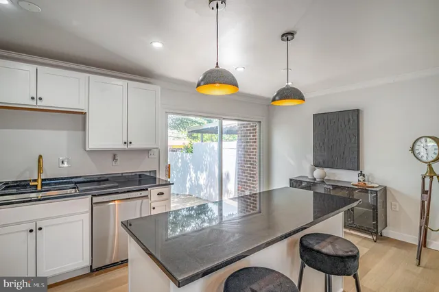 a kitchen with stainless steel appliances granite countertop a stove a sink a refrigerator a dining table and chairs with wooden floor