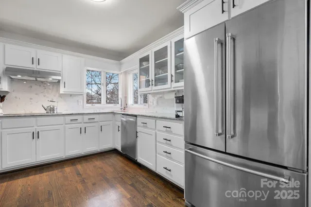 a kitchen with stainless steel appliances white cabinets and wooden floors