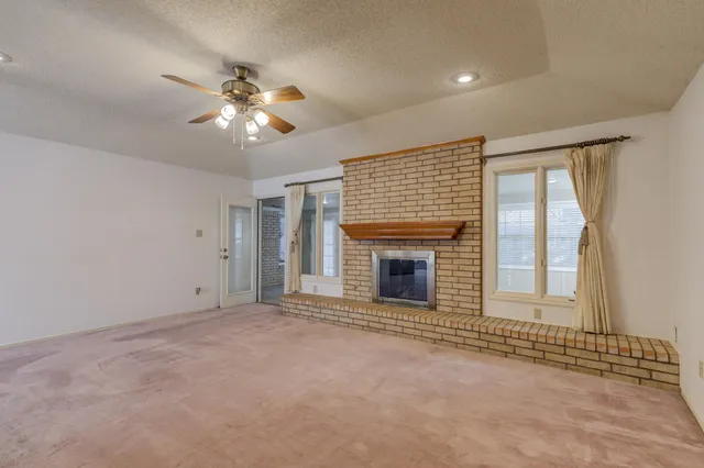 a view of an empty room with a fireplace and a window