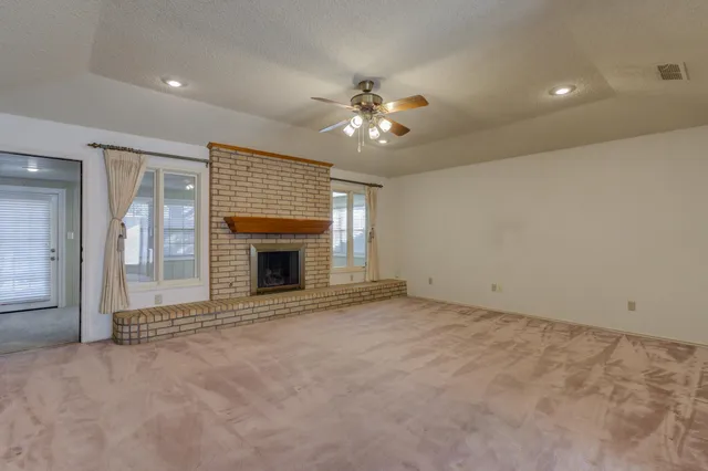 an empty room with windows and fireplace