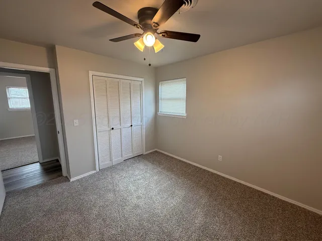 an empty room with a chandelier fan and windows