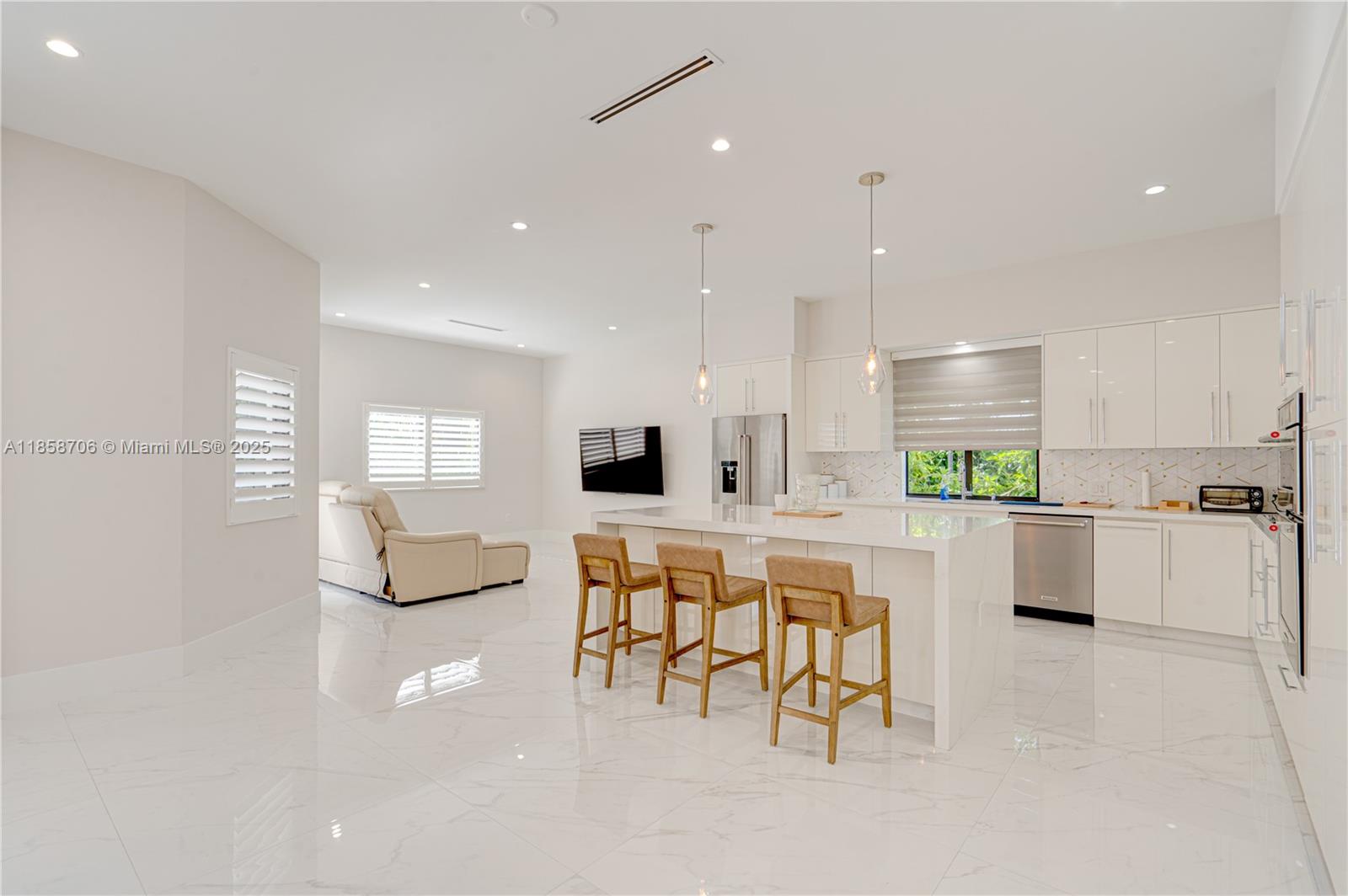 2521 Southwest 105th Avenue Miami, FL 33165 - Photo 6 of 68 a large white kitchen with kitchen island granite countertop a stove a sink a dining table and chairs with wooden floor