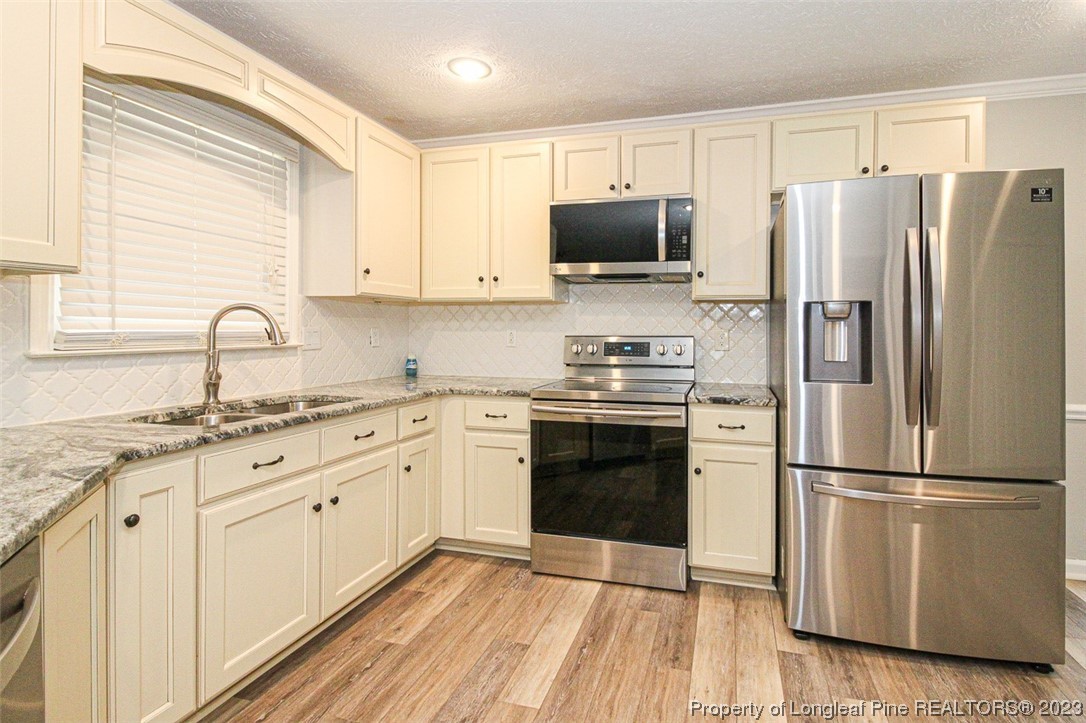 544 Blackbird Road Fayetteville, NC 28314 - Photo 14 of 36 a kitchen with granite countertop appliances a sink cabinets and a window