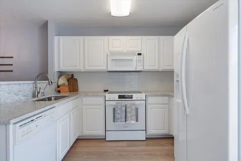 a kitchen with stainless steel appliances granite countertop a sink and cabinets with wooden floor