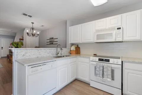 a kitchen with white cabinets and chandelier