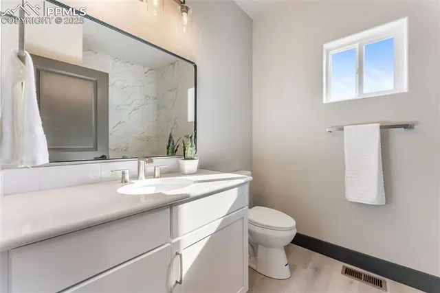 a bathroom with a granite countertop sink a toilet and mirror