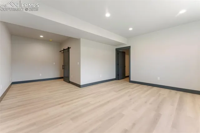 a view of an empty room with wooden floor and closet