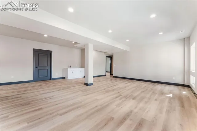 a view of an empty room with wooden floor and closet