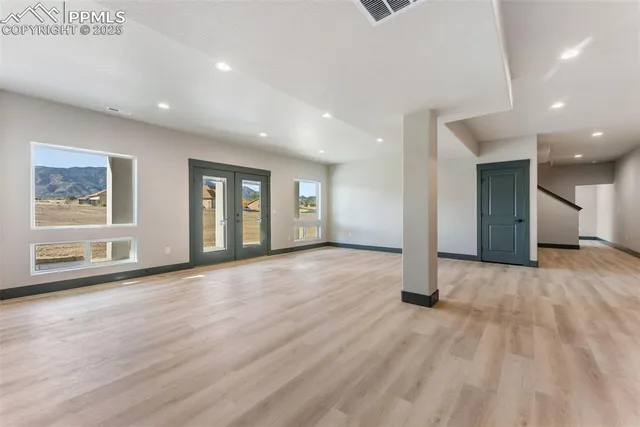 a view of an empty room with wooden floor and windows