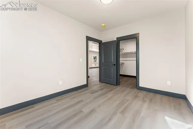 a view of an empty room with wooden floor and closet