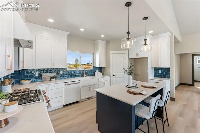 a kitchen with a sink stove and white cabinets with wooden floor
