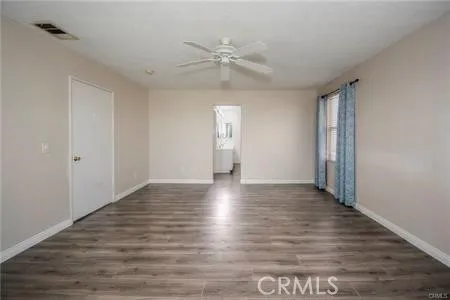 a view of an empty room with wooden floor and window