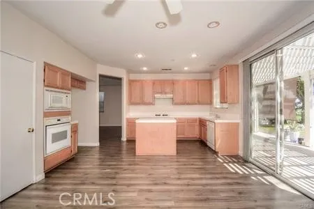 a view of a kitchen with kitchen island a sink wooden floor and counter top space