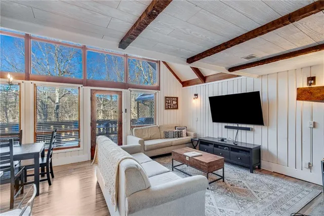 a living room with furniture a flat screen tv and a floor to ceiling window