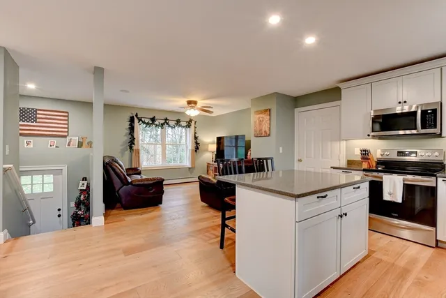 a kitchen with stainless steel appliances granite countertop a stove top oven a sink dishwasher a dining table and chairs with wooden floor