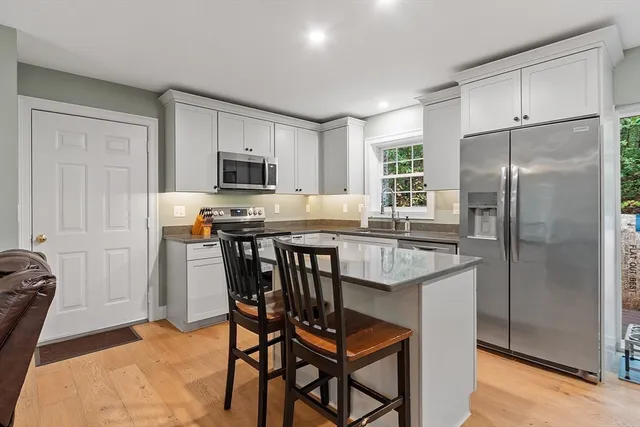 a kitchen with stainless steel appliances granite countertop a stove a refrigerator a sink a dining table and chairs