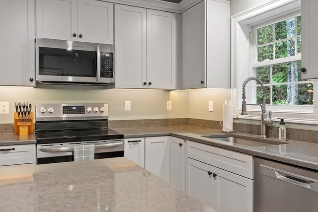 a kitchen with stainless steel appliances granite countertop a stove a sink and a microwave
