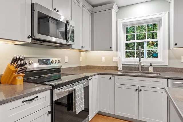 a kitchen with granite countertop white cabinets and a window