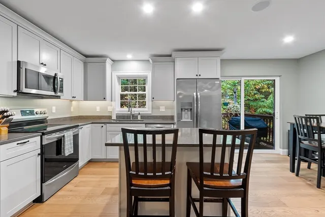 a kitchen with stainless steel appliances granite countertop a stove a refrigerator a kitchen island a table and chairs