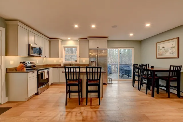 a open kitchen with stainless steel appliances granite countertop a stove a sink a dining table and chairs