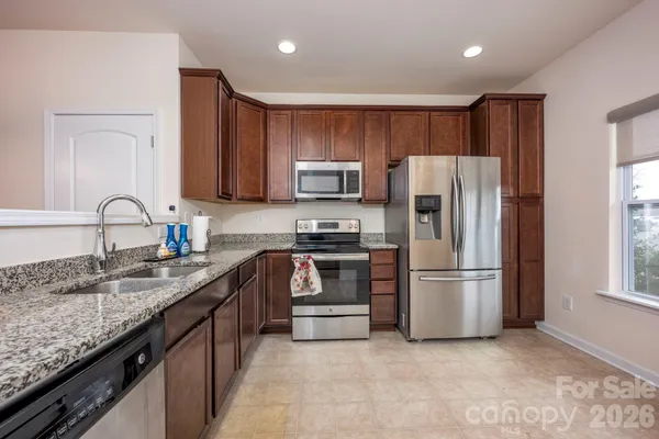 a kitchen with refrigerator a microwave a sink and cabinets