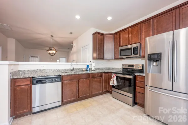 a kitchen with stainless steel appliances granite countertop a refrigerator a stove top oven a sink and dishwasher