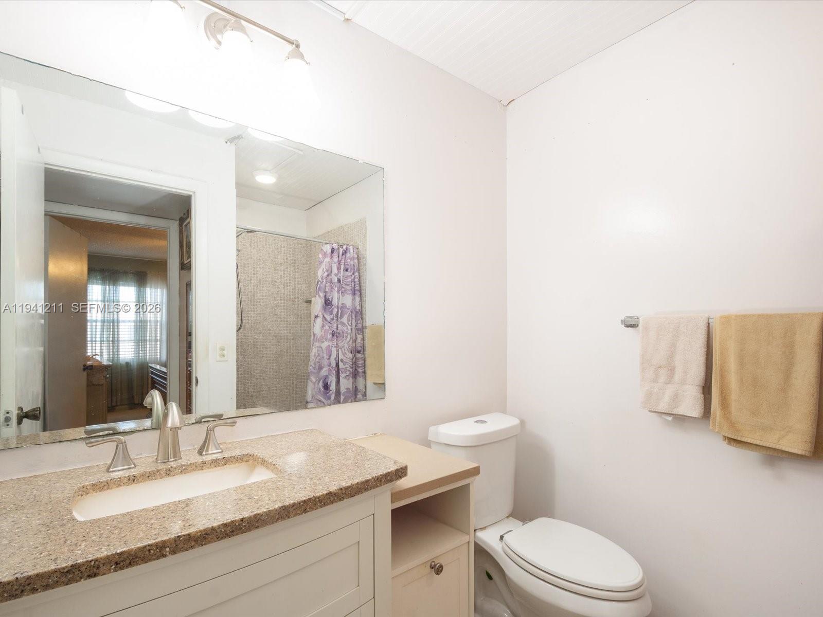 414 Capri H, Unit 414 Delray Beach, FL 33484 - Photo 10 of 19 a bathroom with a granite countertop sink mirror vanity and toilet