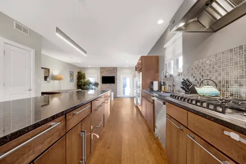 a kitchen with stainless steel appliances a refrigerator a sink dishwasher a stove and a microwave oven with wooden floor