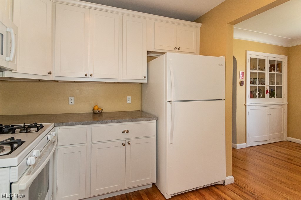 2419 Kingston Road Cleveland, OH 44118 - Photo 14 of 34 Kitchen featuring white cabinets, light hardwood flooring, crown molding, dark countertops, and white appliances