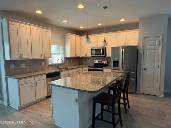 a kitchen with kitchen island granite countertop a sink a center island stainless steel appliances and cabinets