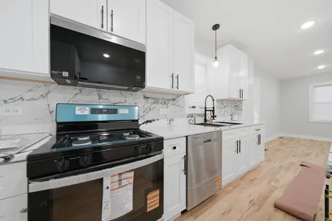 a kitchen with stainless steel appliances a stove a microwave a sink and cabinets