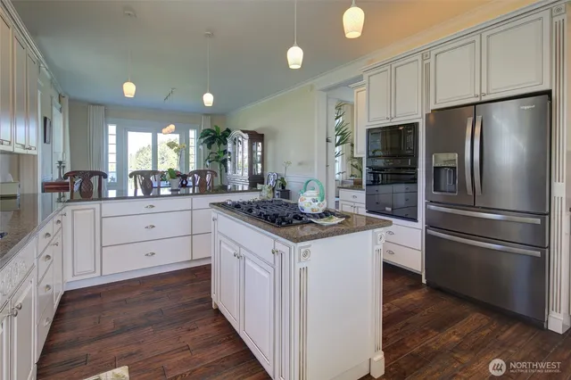 a kitchen with stainless steel appliances granite countertop a stove a refrigerator and a sink with wooden cabinets