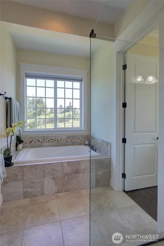 a spacious bathroom with a tub shower and mirror
