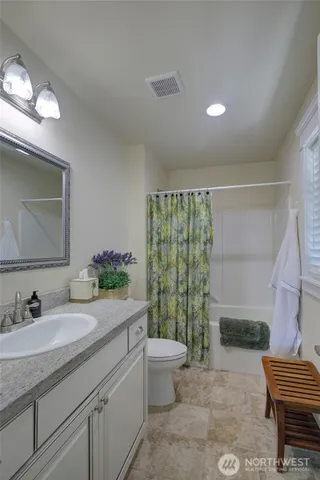 a spacious bathroom with a granite countertop sink a toilet a mirror and shower
