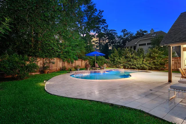 a view of swimming pool with lawn chairs under an umbrella