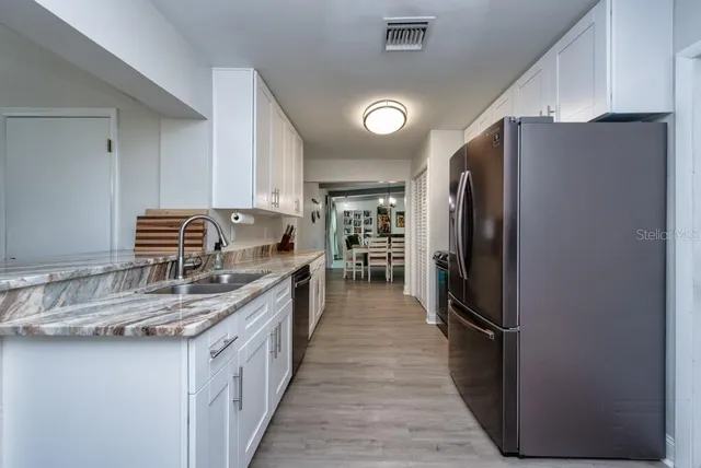 a kitchen with stainless steel appliances granite countertop a refrigerator and a sink