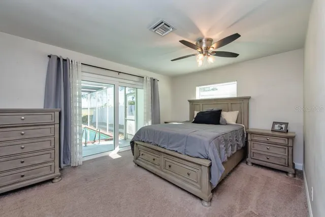 a spacious bedroom with a bed a dresser and a chandelier